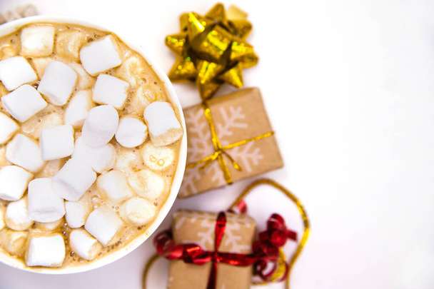 Coffee with marshmallows on a white background with gifts and holiday bows.Hot winter drink. Cocoa and cappuccino. - 写真・画像