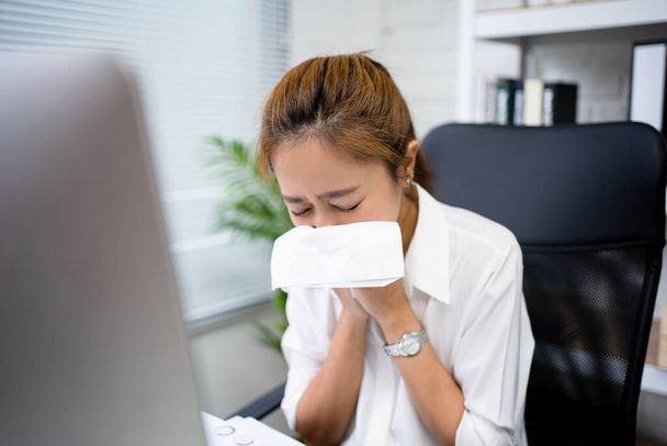 Young business woman is sick. She sneezes and coughs in the office. - Foto, Bild