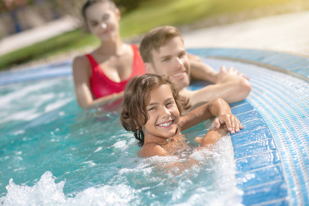 Happy boy with parents in pool water - Zdjęcie, obraz