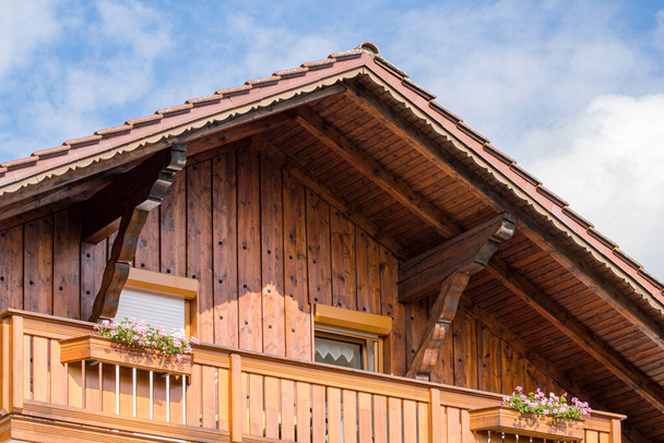 Casale in legno con cielo nuvoloso e balcone con fiori - Foto, immagini