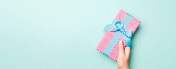 女性の手は、色の紙に包まれたクリスマスや他の休日の手作りプレゼントを与える。プレゼントボックス、ブルーテーブルのギフトの装飾、コピースペース付きのトップビュー. - 写真・画像