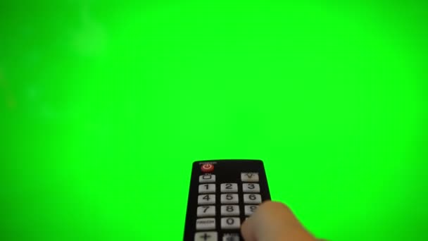 Ανδρικό χέρι με τηλεχειριστήριο που δείχνει στην οθόνη της τηλεόρασης. Κλειδί πράσινου χρώματος. - Πλάνα, βίντεο