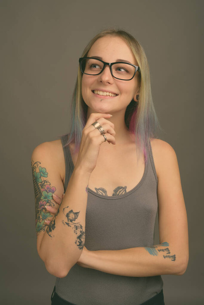 Studio shot of young beautiful rebellious woman with multicolored hair against gray background - Foto, Bild