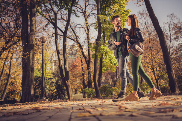 Full body profile side photo of positive couple go in autumn september town center park path speak wear jacket rucksack - Foto, Imagem