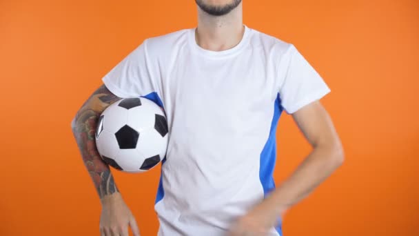 Jogador de futebol pega bola isolada em blackground laranja - Filmagem, Vídeo