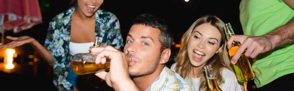 Ιστοσελίδα κεφαλίδα του ανθρώπου πίνοντας μπύρα κοντά ενθουσιασμένοι φίλοι σε εξωτερικούς χώρους το βράδυ   - Φωτογραφία, εικόνα
