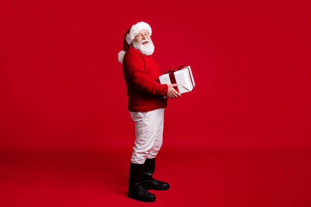 Full body profile side photo old man santa claus headwear hold big x-mas gift box prepare fairy magic newyear event wear pants trousers boots isolated bright shine color background - 写真・画像