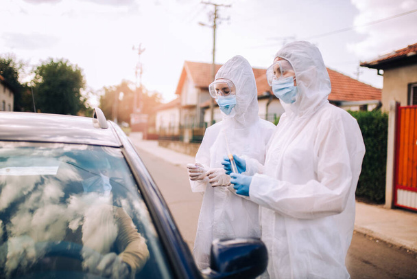 冠ウイルス感染の可能性をテストするために人から綿棒を取る保護訴訟の医師 - 写真・画像