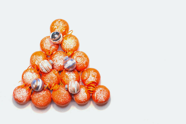 Kerstboom vorm gemaakt met sappige mandarijnen (mandarijnen) en rode bogen op kleur achtergrond, bovenaanzicht. Ruimte voor tekst.Vrolijk kerstfeest en gelukkig Nieuwjaar. Vlakke plaat - Foto, afbeelding