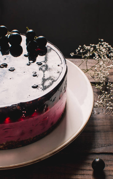 Cheesecake mousse cake with black currant. Delicious cake with berries on a wooden table. - Foto, imagen