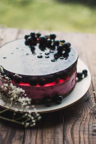 Cheesecake mousse cake with black currant. Delicious cake with berries on a wooden table. - Photo, Image