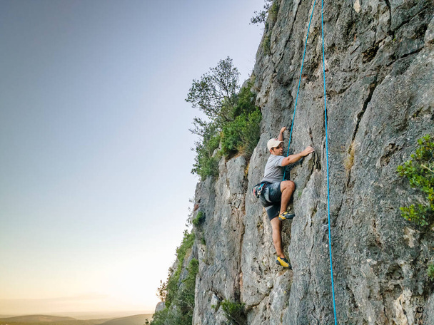 Mann klettert in Portugal auf steilen, flachen Felsen - Foto, Bild