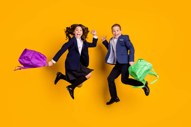 Full length body size view of two nice attractive small little cheerful friends friendship jumping having fun new academic year isolated bright vivid shine vibrant yellow color background - Foto, imagen