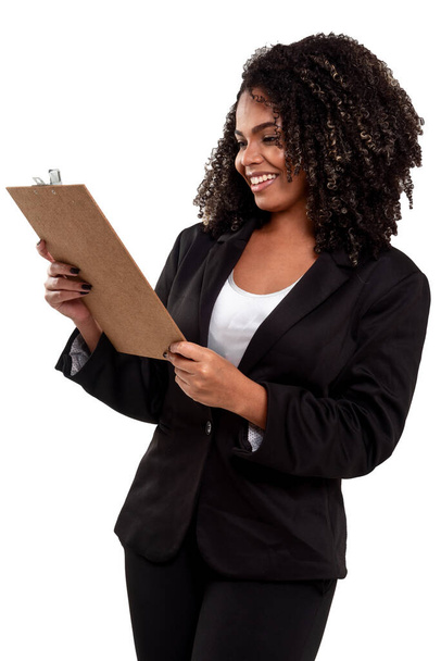 Veselý a usmívající se výkonný černošky brazilská žena izolované na bílém pozadí, pracuje se schránkou a drží pero. - Fotografie, Obrázek