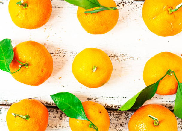 Pequenas tangerinas são dispostas em três fileiras e jazem em uma mesa de madeira branca. Conceito de alimentação saudável. - Foto, Imagem