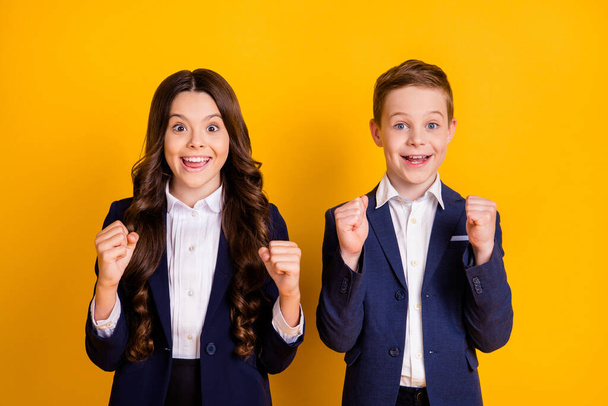 Portrait of his he her she attractive cheerful cheery lucky schoolkids learners nerds holding fists great success a-mark pass test isolated bright vivid shine vibrant yellow color background - Foto, Imagem