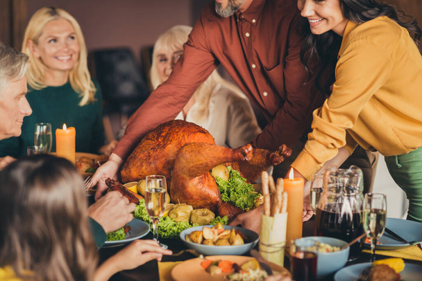 Two parents put decorated apples stuffed turkey on table holiday dinner family reunion living room indoors - 写真・画像