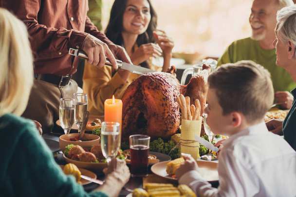 Photo of family meeting served table thanks giving dinner slicing stuffed grilled turkey living room indoors - Foto, imagen