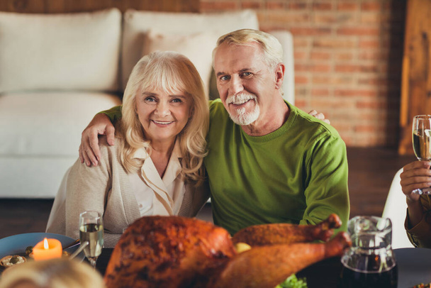 Portrait of thanks giving meeting elderly couple embracing sit table dinner young living room indoors - Fotoğraf, Görsel