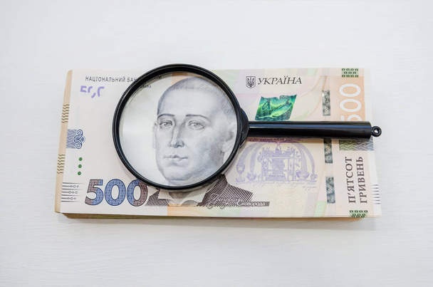 Une pile de billets de banque en hryvnia et une loupe. Fond clair. Beaucoup d'argent. Hryvnia ukrainienne. Vue d'en haut. - Photo, image