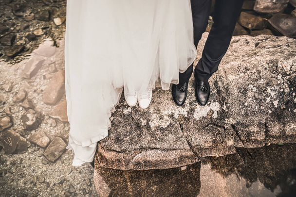 Legs of bride and groom standing on big gray stone - Photo, Image