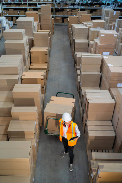 Trabajador de almacén logístico entregando cajas en un carro - Foto, imagen