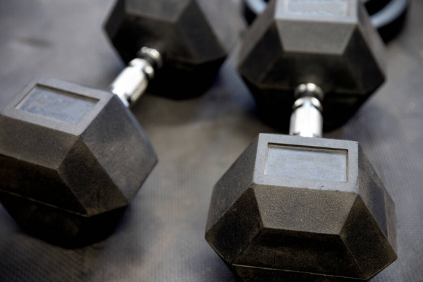 Dumbbells or weights on black rubber flooring tiles inside gym Concept for workout - Photo, Image
