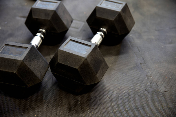 Spor salonundaki siyah lastik döşeme döşemeleri üzerinde dambıllar ya da ağırlıklar. Egzersiz için kavram - Fotoğraf, Görsel
