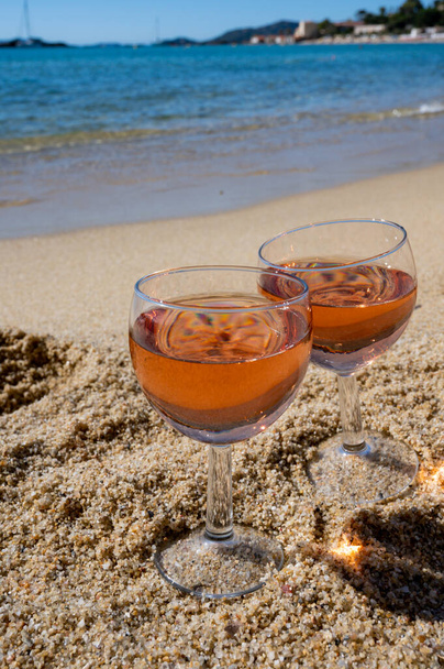 Dos copas de vino de rosas locales en la playa de arena blanca y el mar Mediterráneo azul en el fondo, cerca de Le Lavandou, Var, Provenza, Francia - Foto, Imagen