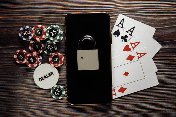 Asma kilitli akıllı telefon, poker fişleri ve iskambil kağıtları. Hukuk kavramı ve kumar yönetmeliği - Fotoğraf, Görsel