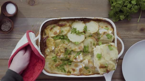 Plat gelegd. Vers uit de oven gebakken geschulpte aardappelen garneren met peterselie in een witte keramische bakvorm. - Video