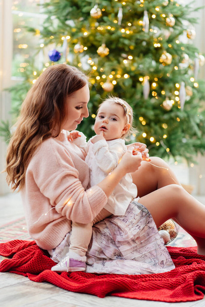 mother and daughter sitting at Christmas tree.  - Foto, Bild