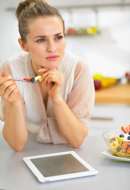Young woman with tablet pc eating fruit salad - Photo, Image