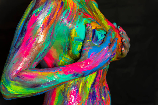 A naked woman is painted with colorful paint in a home environment - Foto, Imagem