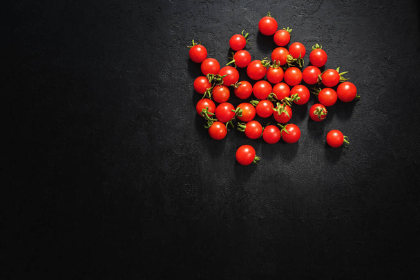 Tomates cherry maduros sobre fondo negro. Vista superior. Copiar espacio - Foto, Imagen