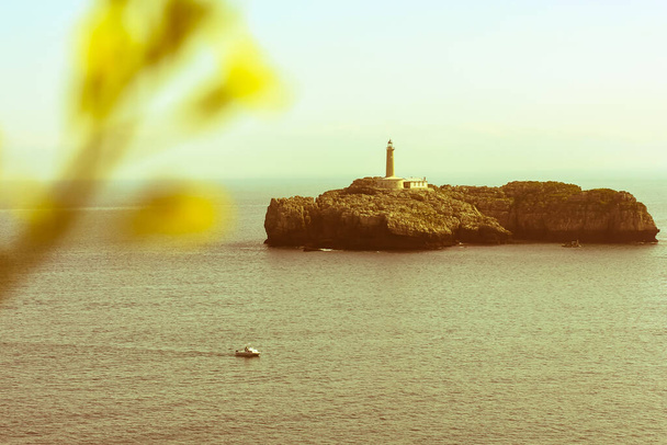 Hermosa vista de la isla y el faro de Mouro - Isla y Faro de Mouro - y un pequeño barco. Santander, España - Foto, imagen