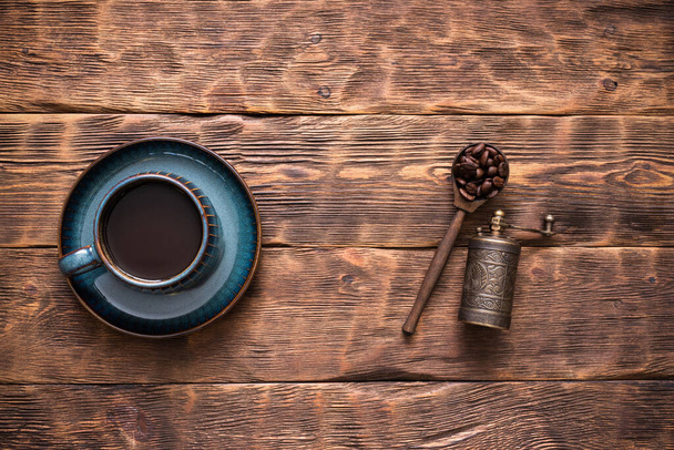 A cup of black coffee and coffee beans on the scoop on the brown wooden table background. - Foto, immagini