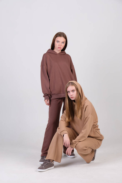 Pair of fashionable models posing in studio in brown and beige casual suits for clothing catalog. Examples of autumn female fashion. Copy space. - Foto, Imagem