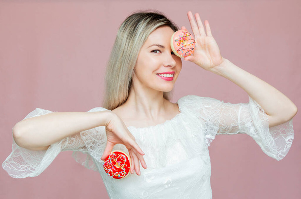 beautiful girl playing with donuts on a pink background. Diet, dieting concept. Junk food, weight loss - Photo, image
