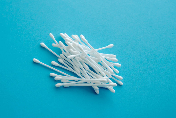 Cotton ear swabs sticks on blue background. close up. Image with selective focus, noise effect and toning. Top view. Flat lay. - Photo, image