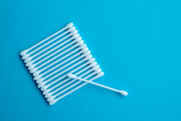 Cotton ear swabs sticks on blue background. close up. Image with selective focus, noise effect and toning. Top view. Flat lay. - Foto, imagen