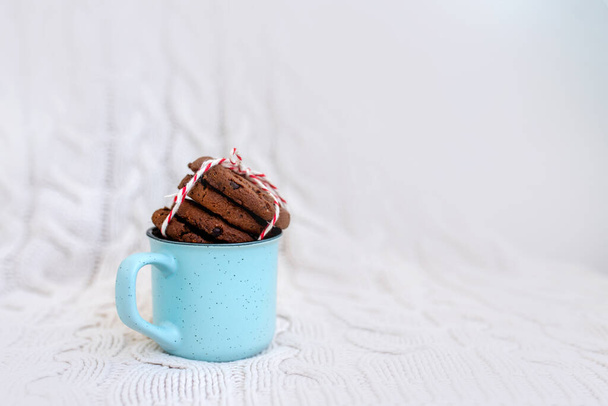 Stapel smakelijke chocolade kerstkoekjes op een licht gekleurde achtergrond. Blauwe mok. Beeld met selectieve focus, ruis effect en toning. Bovenaanzicht. - Foto, afbeelding