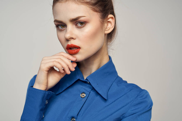 Porträt einer schönen Frau mit roten Lippen auf hellem Hintergrund und blauem Hemd - Foto, Bild