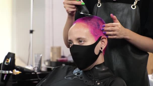 Fryzjerka strzyże krótkie włosy w salonie podczas epidemii z maską na twarzy.. - Materiał filmowy, wideo