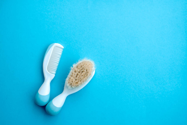 Set of baby accessories for hygiene. Two white hair comb crest brushes with handle for all types white soap, isolated on blue copy space background. flat lay.Top view. - Photo, Image