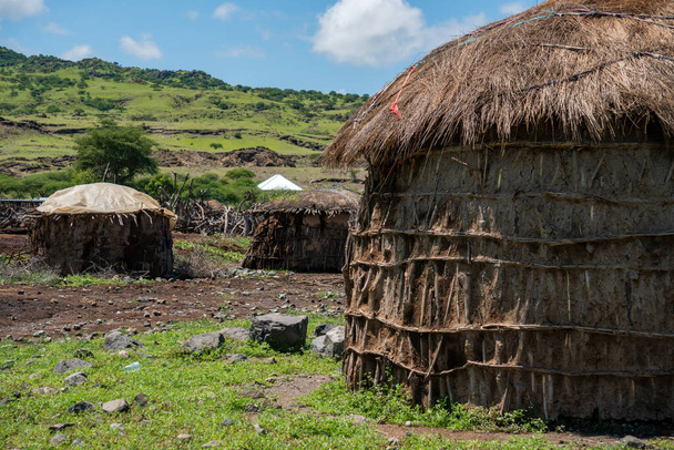 Pueblo Maasai tradicional con cabañas redondas de arcilla en la zona de Engare Sero cerca del lago Natron y el volcán Ol Doinyo Lengai en Tanzania, África - Foto, imagen