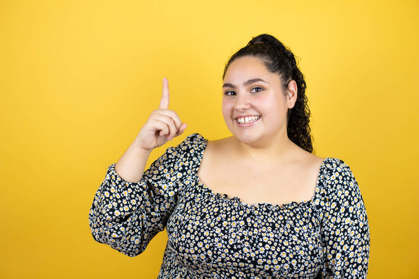 Young beautiful woman with curly hair over isolated yellow background surprised and thinking with her finger on her head that she has an idea. - Photo, Image
