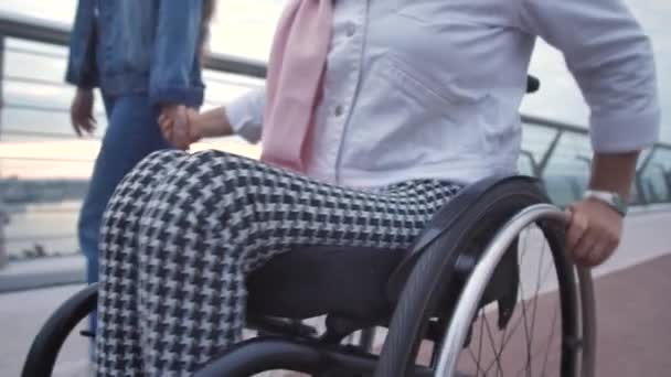 Взрослая женщина в инвалидном кресле и ее дочь на прогулке - Кадры, видео