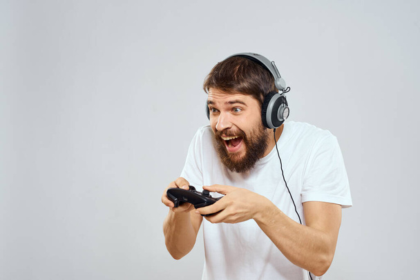 Man in headphones with gamepad playing hobby entertainment lifestyle light background - Zdjęcie, obraz