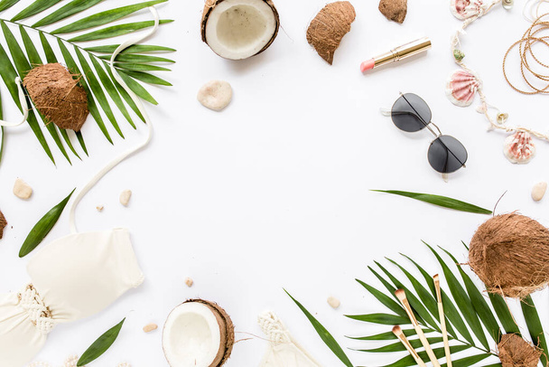 Feminine beige swimsuit beach accessories, tropical palm leaf branches, coconuts on white background with empty space for text. Flat lay, top view.  - Фото, зображення